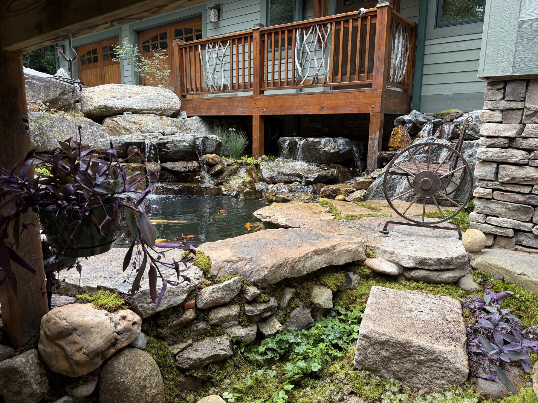 Natural stone stepping stones and moss garden beside a koi pond with waterfalls