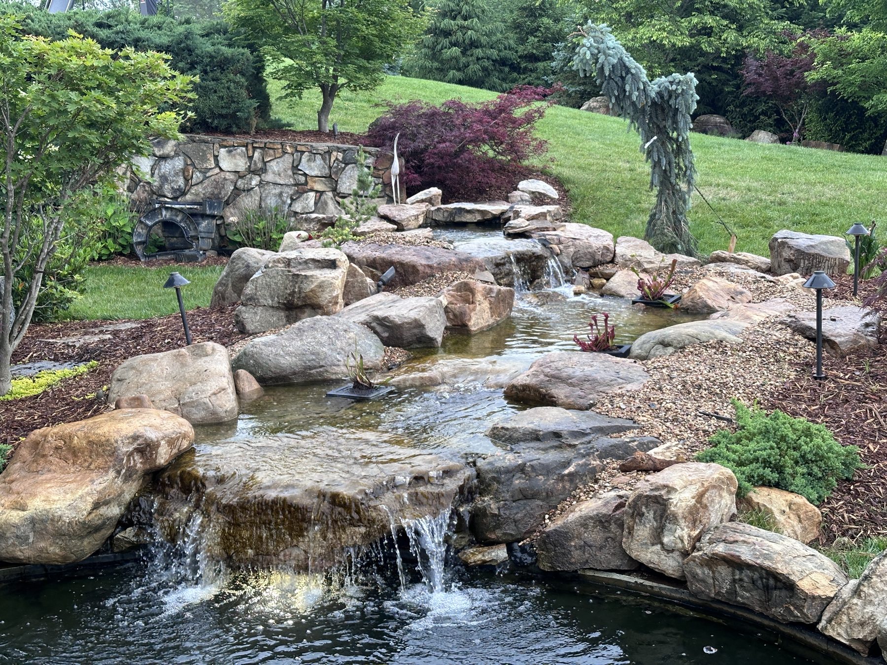 Natural boulder waterfall and stream feeding a koi pond